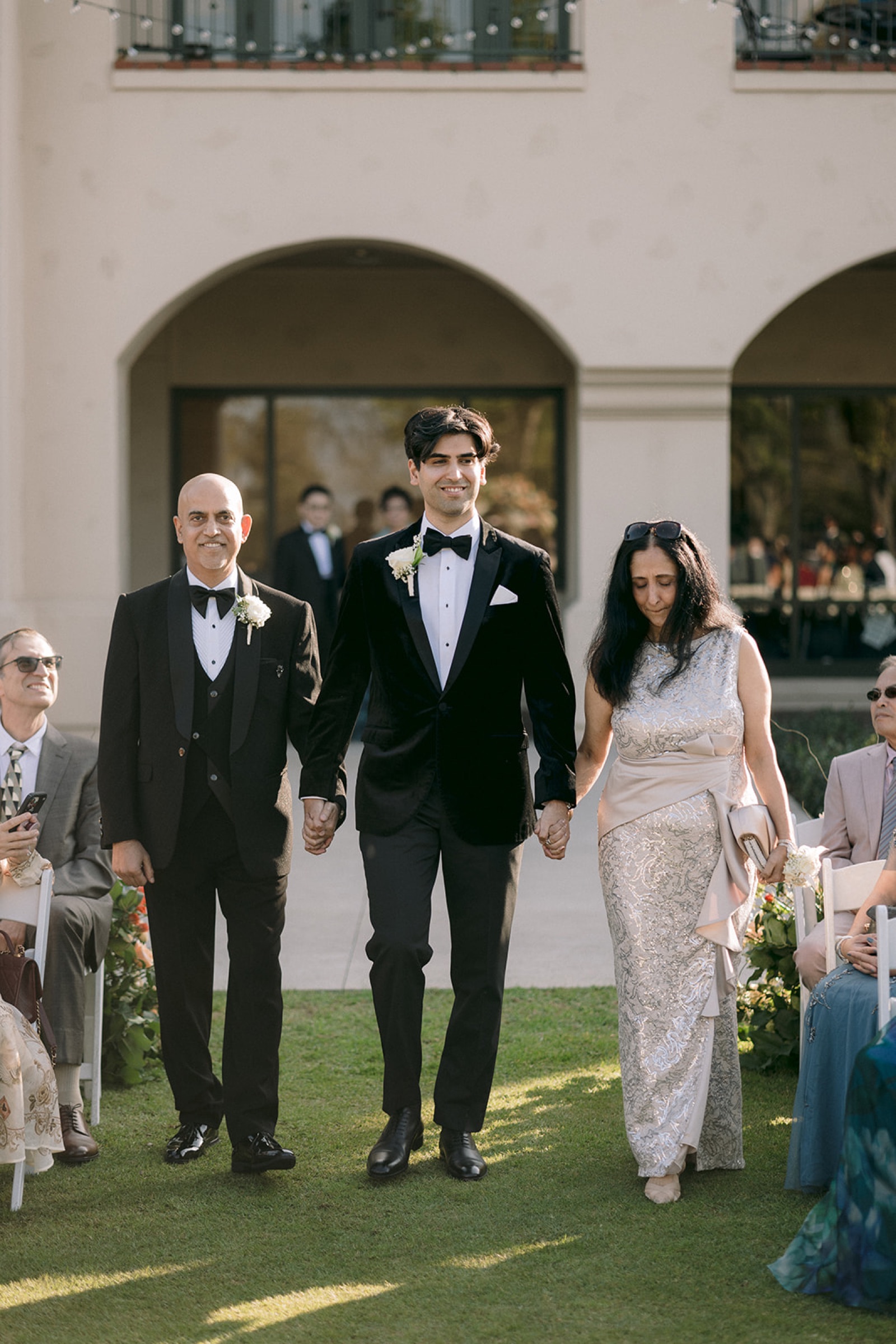 Groom escorted by parents at the ceremony