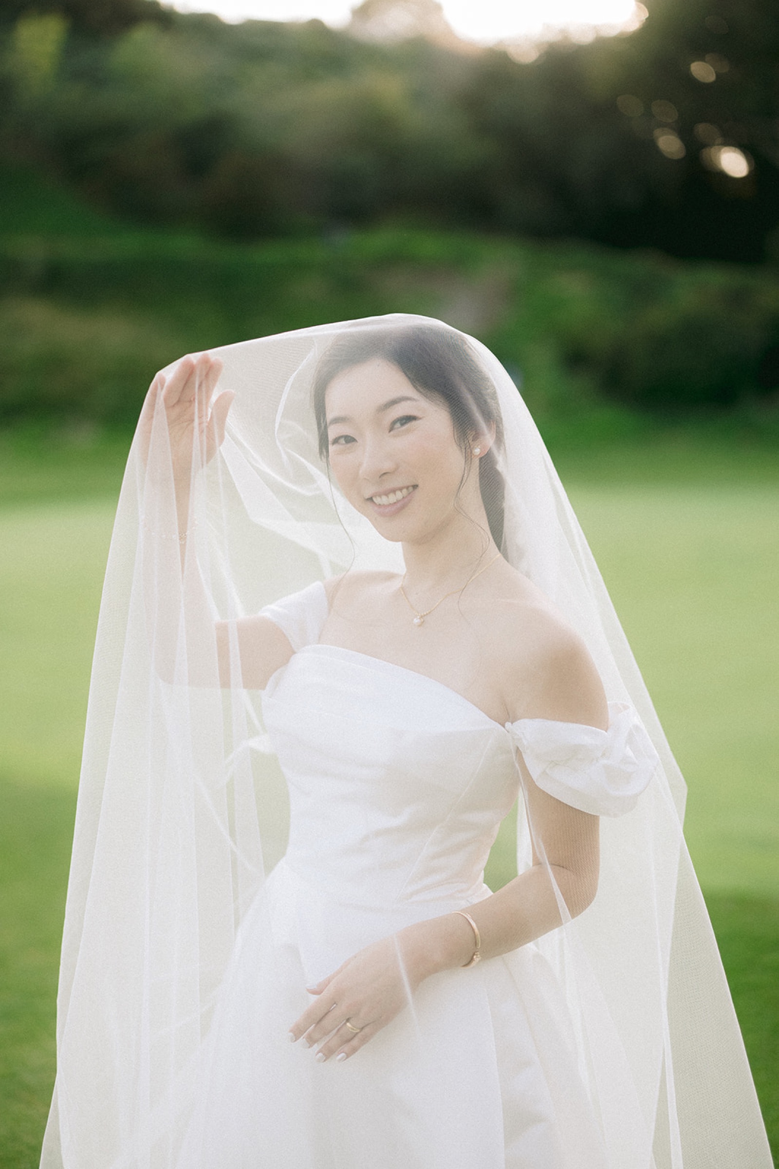 Bride with veil in golden hour light on the green