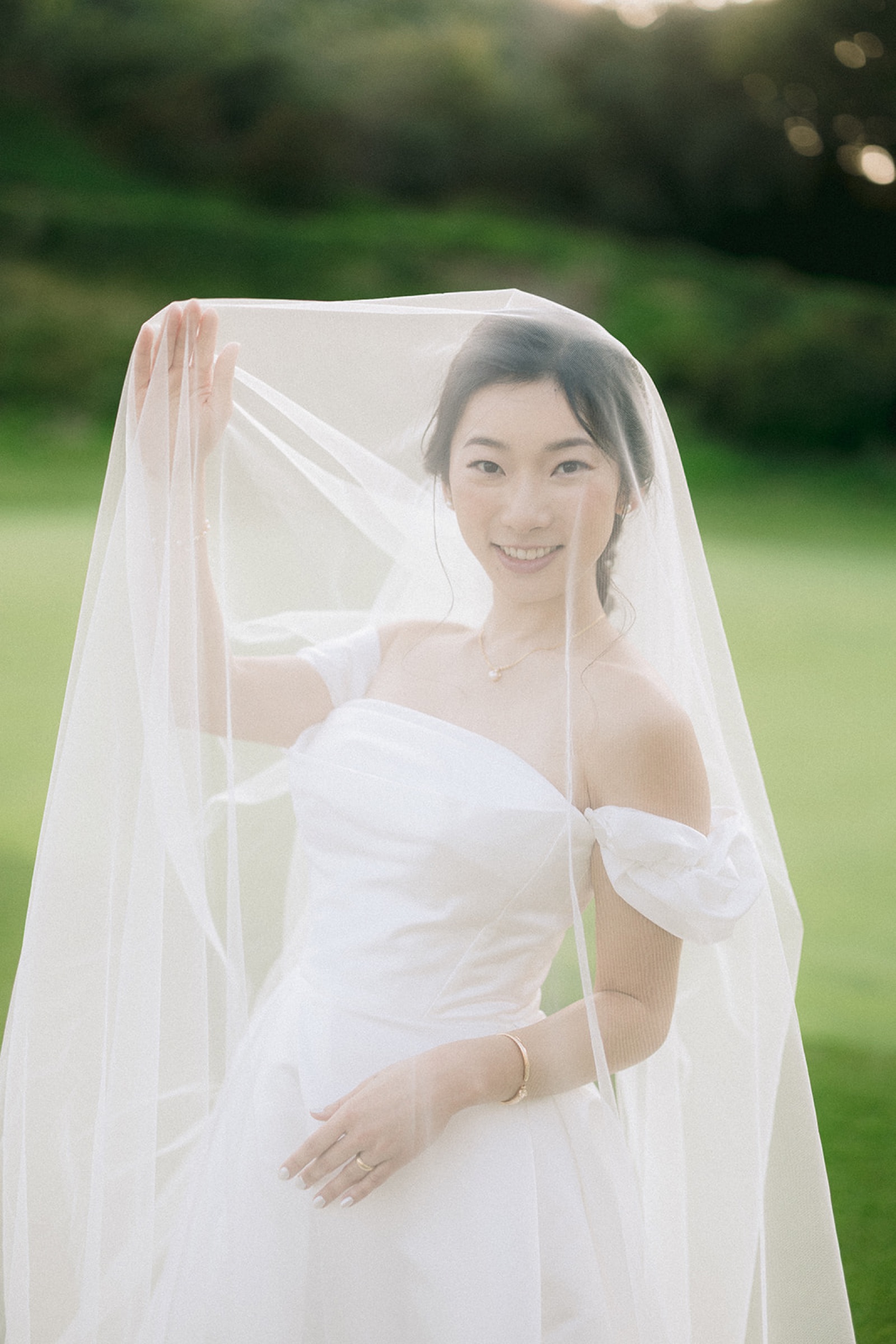 Bride sitting on the golf course with veil and golden sunlight