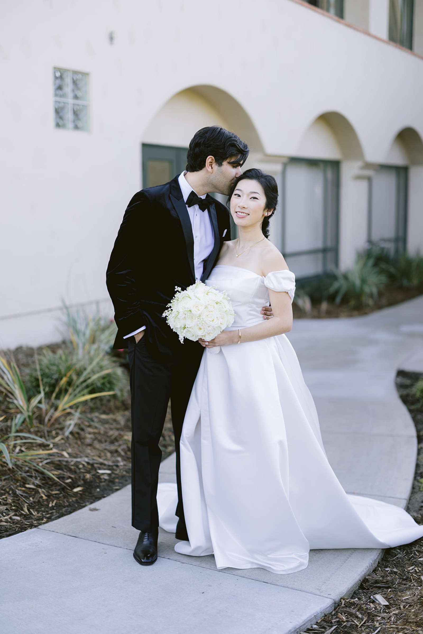 Groom kissing bride on forehead after first look